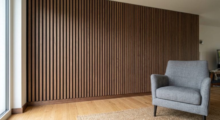 Akustikpaneele aus dunklen Holzlamellen mit schwarzer Filzauflage, gleichmäßig an einer Wohnzimmerwand montiert