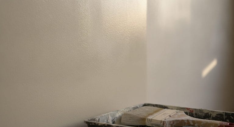 Frisch gestrichene Wand mit Malerpinsel, Nahaufnahme
